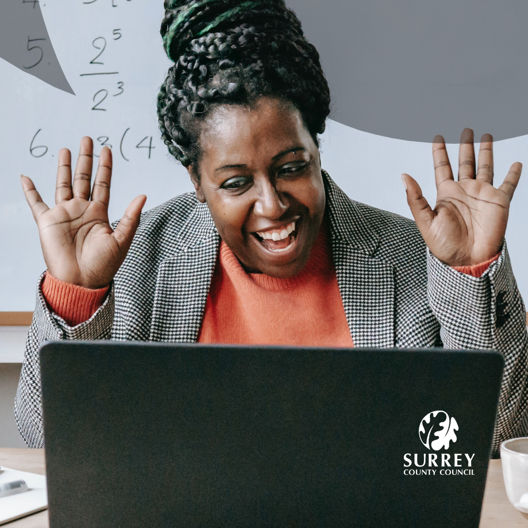 An image of a lady, smiling, using a laptop. Surrey County Council logo.