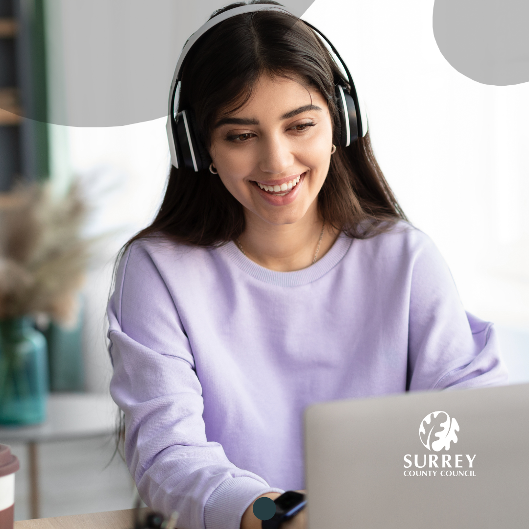 An image of a lady smiling, using a laptop computer